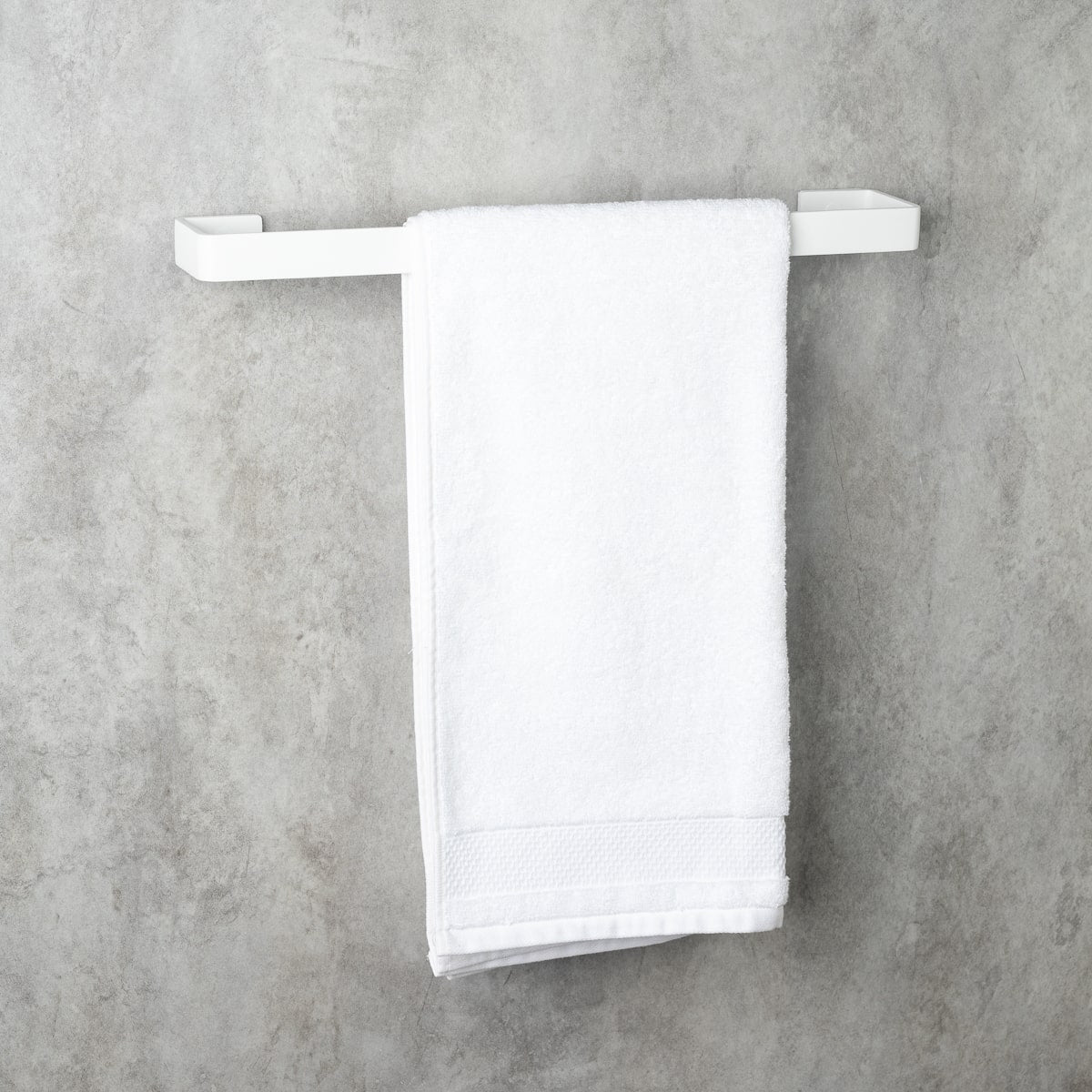 white color holder, made of aluminum, front view, holding a white towel, modern bathroom accessory